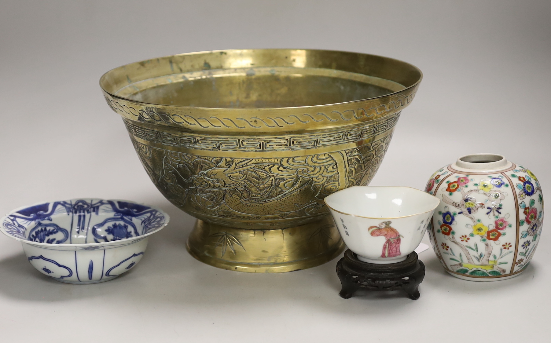 An early 20th century Chinese famille rose tea bowl and stand together with a brass ‘dragon’ bowl, a blue and white bowl and a jar